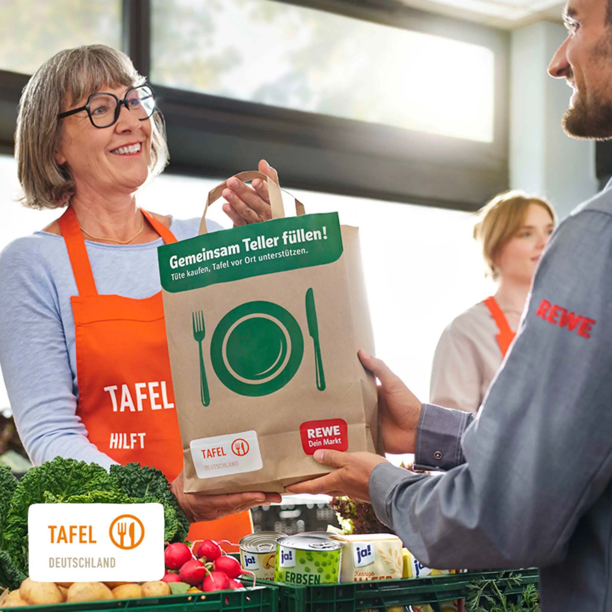 Eine Helferin der Tafel gibt einer anderen Person eine Tüte mit Lebensmitteln.