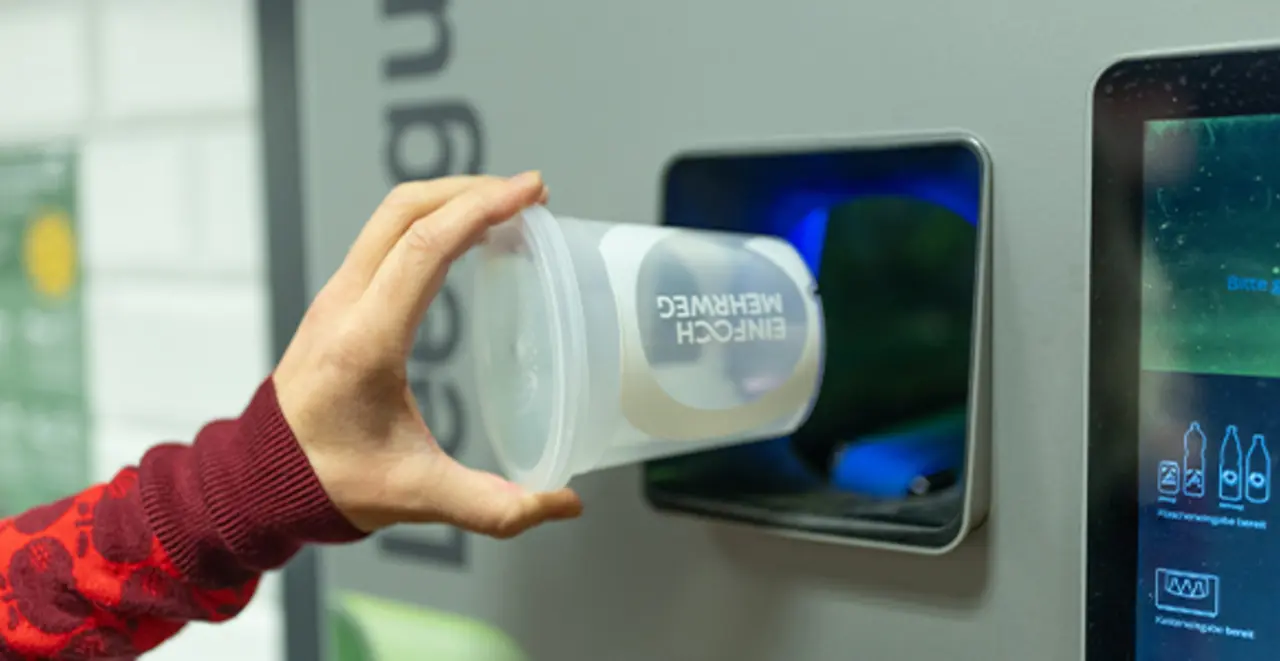 Eine Person legt einen Mehrweg-Pfandbehälter in den Mehrweg-Pfandautomaten.
