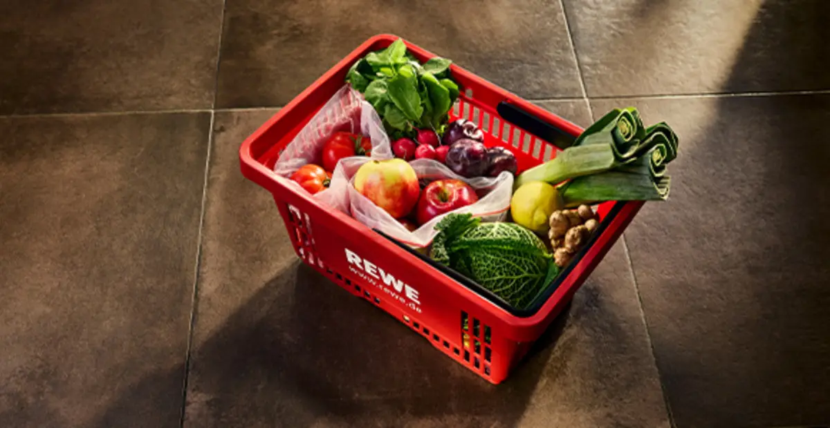 Ein roter REWE Einkaufskorb gefüllt mit unverpackten Produkten.