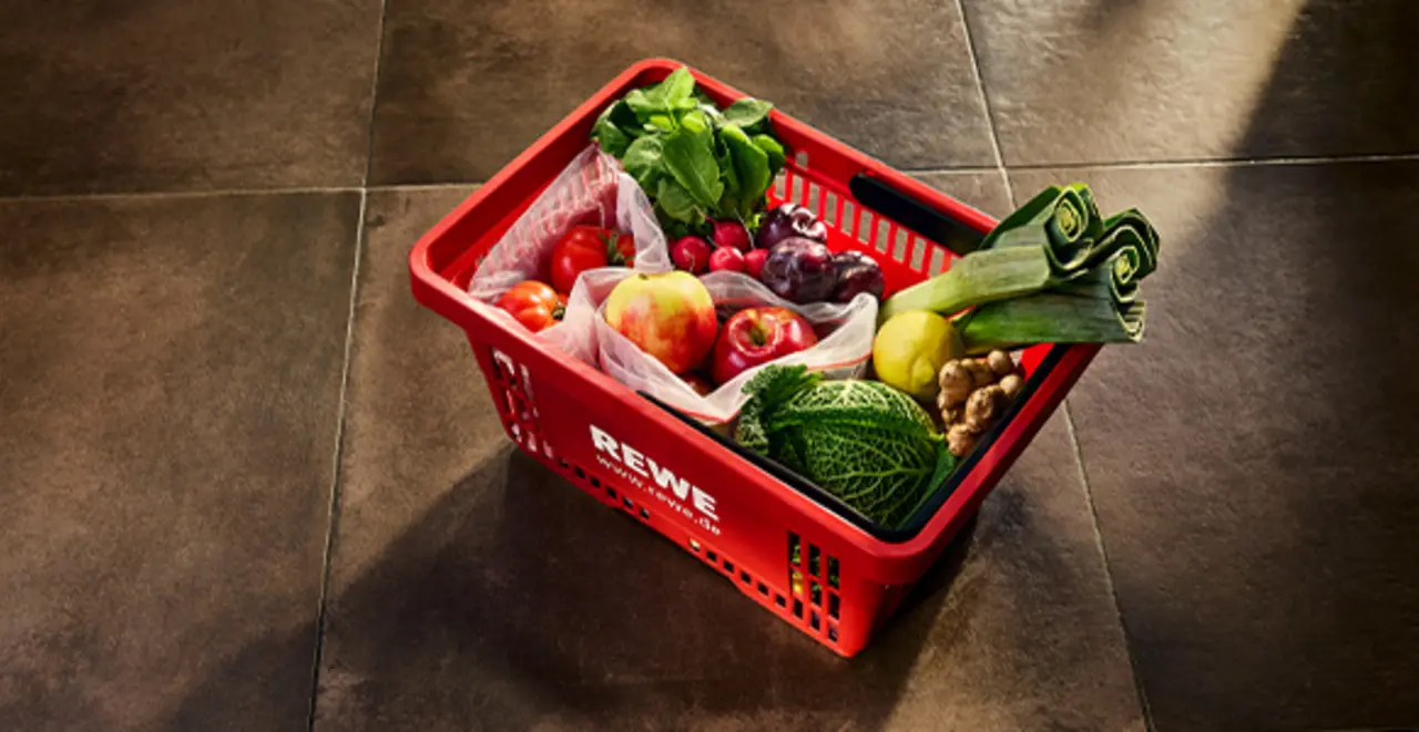 Ein roter REWE Einkaufskorb gefüllt mit unverpackten Produkten. 