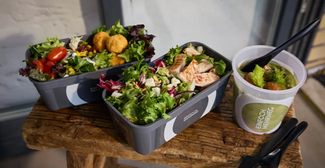 Verschiedene Mehrweg-Pfandbehälter mit frischem Salat und Suppe.