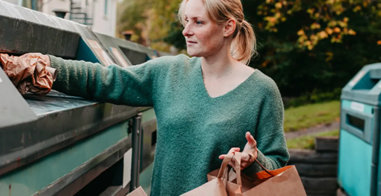 Eine Person wirft Altpapier in einen Altpapier-Container.
