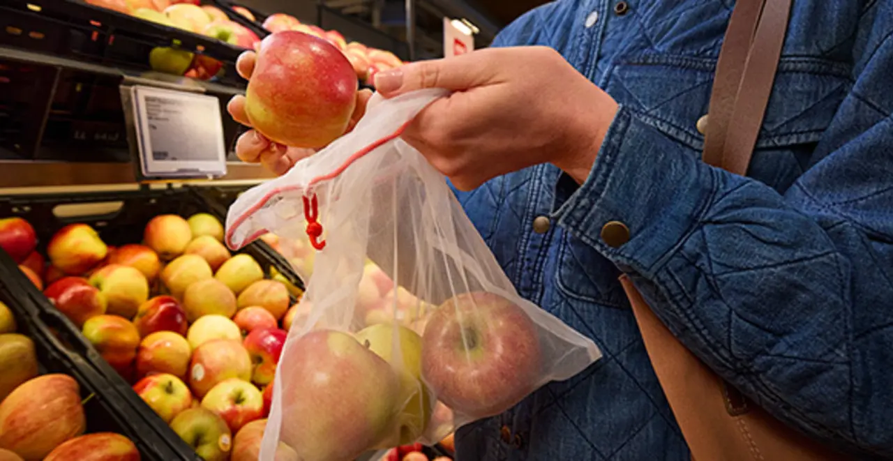 Eine Person legt unverpackte Äpfel in ein Mehrweg-Frischenetz.