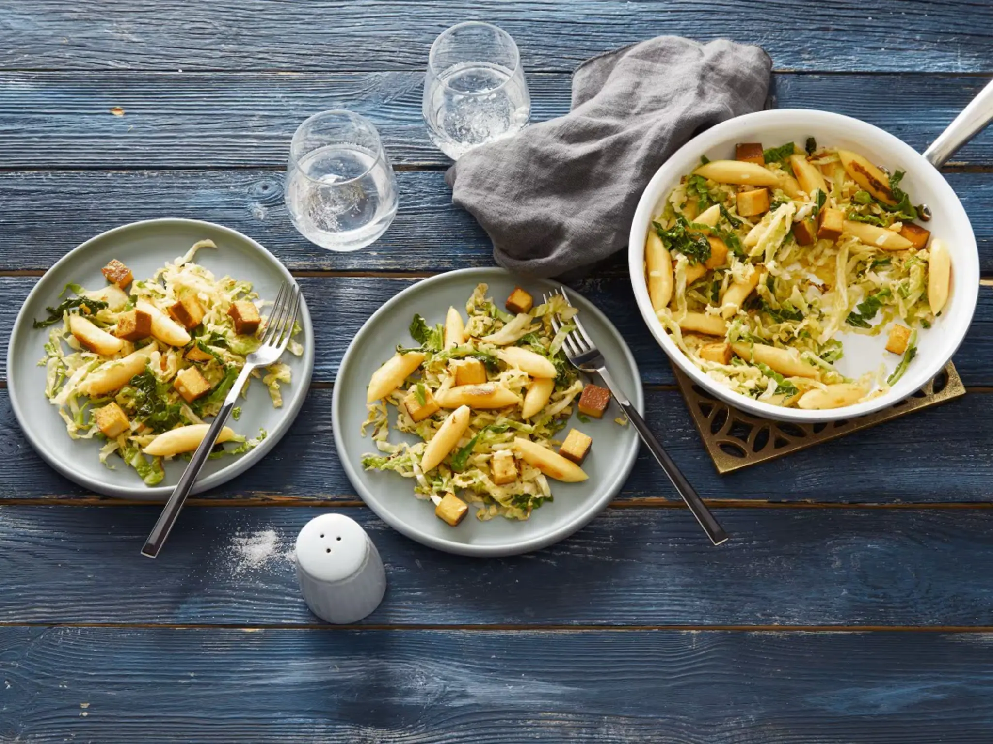 Auf einem gedeckten Tisch steht eine Wirsingpfanne mit Räuchertofu und Schupfnudeln.