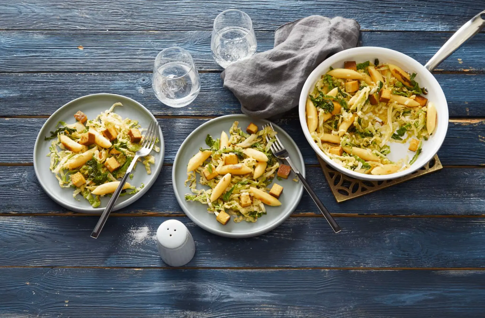 Auf einem gedeckten Tisch steht eine Wirsingpfanne mit Räuchertofu und Schupfnudeln.