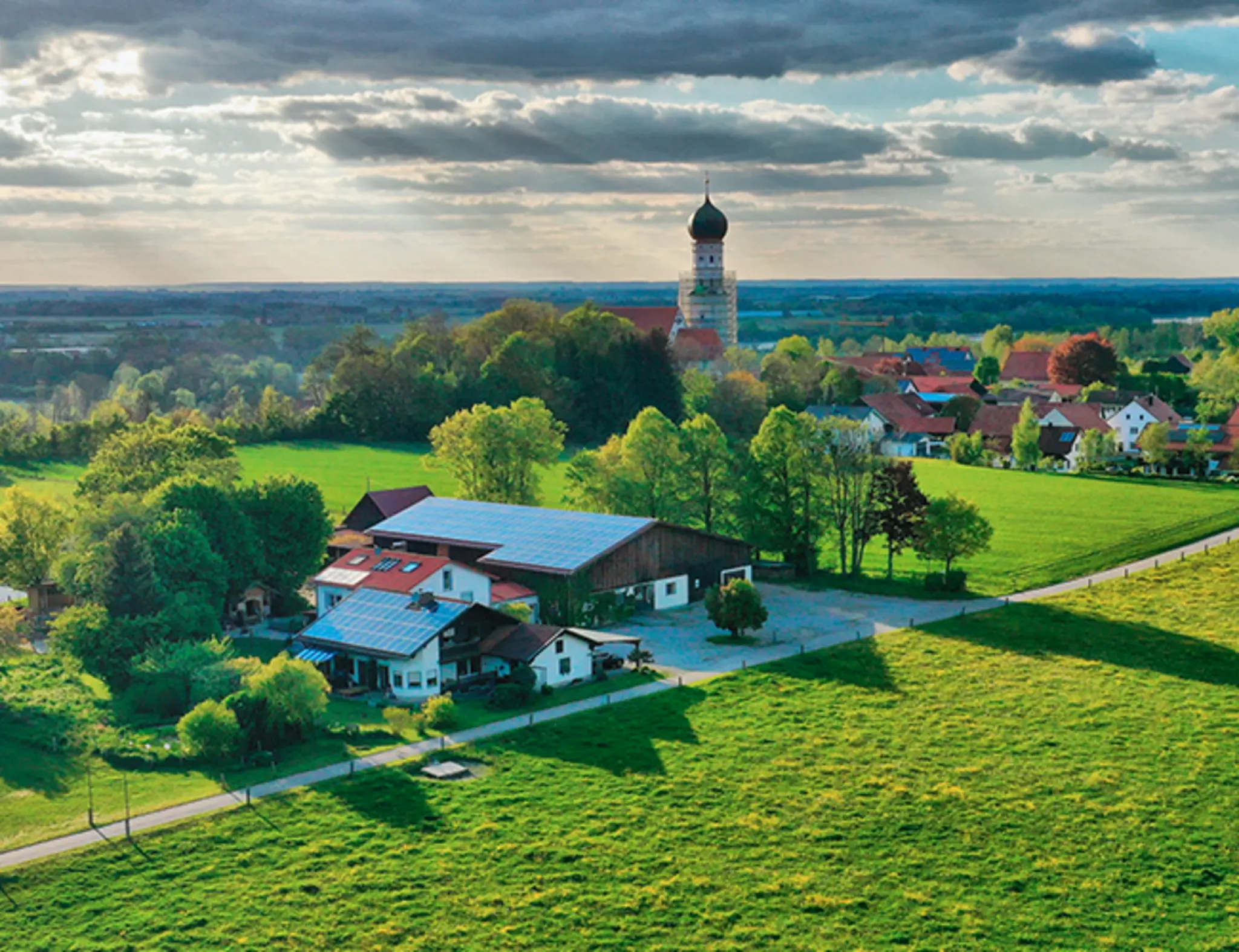 Der Jegglhof inmitten von Bäumen und Weiden. 