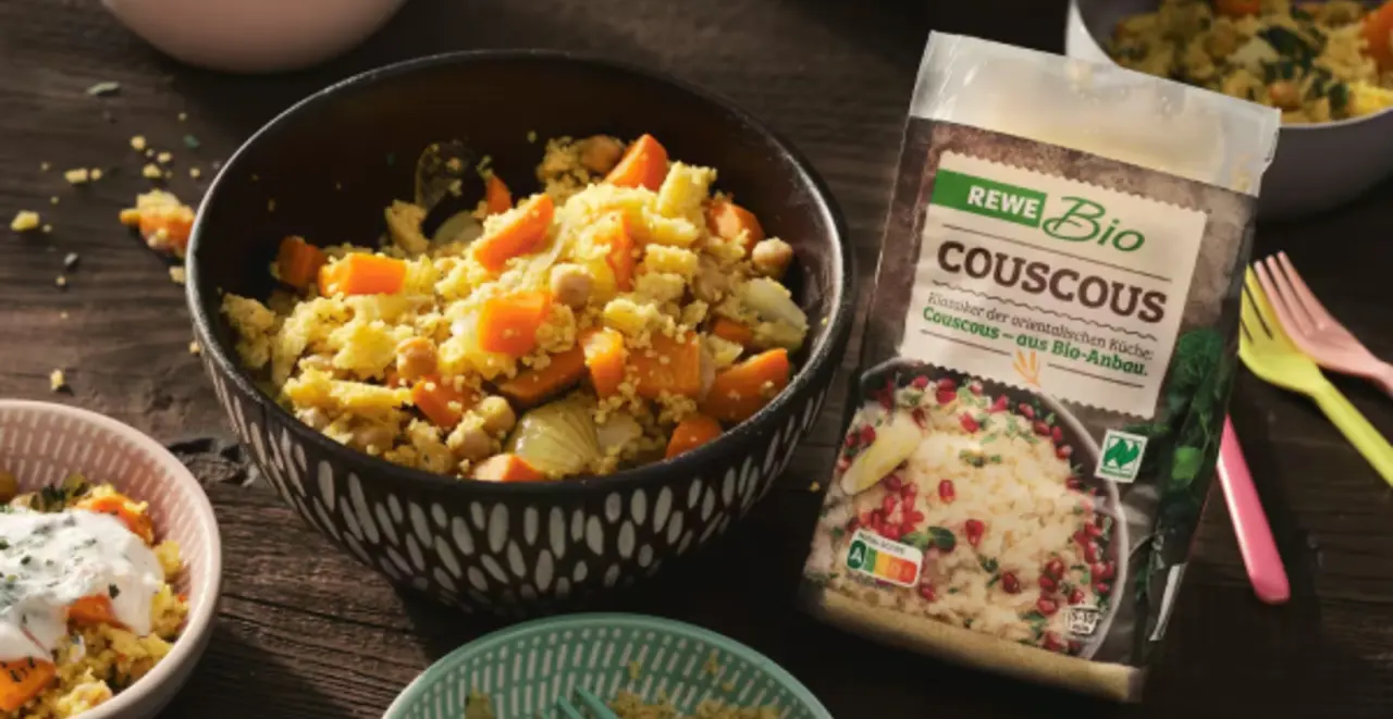 Zwei Schüsseln gefüllt mit Couscous und Gemüse. Rechts daneben eine Packung REWE Bio Couscous.