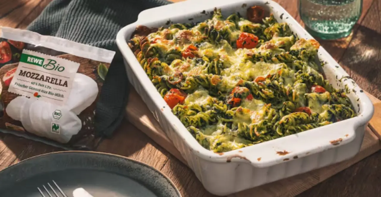 Eine Auflaufform mit Nudel-Spinatauflauf. Links daneben eine Packung REWE Bio Mozarella. 