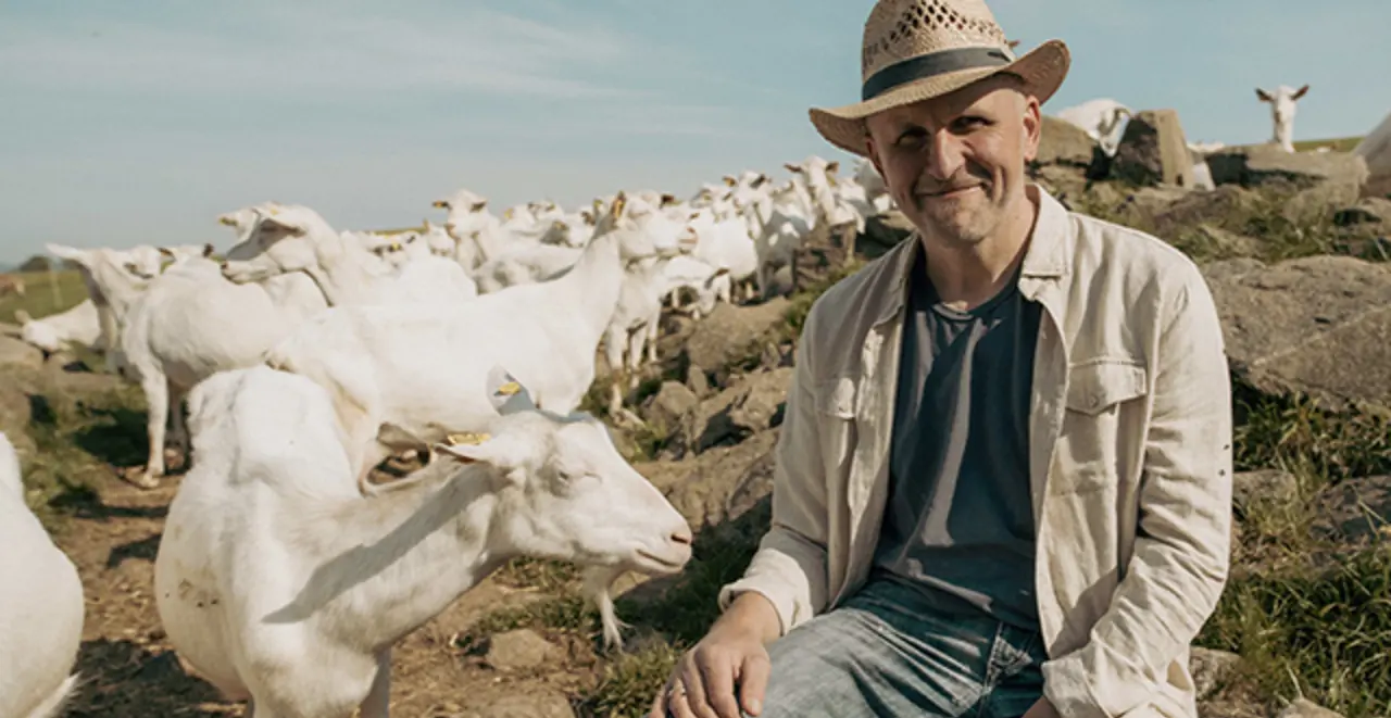 REWE Bio Landwirt Franz Haslehner mit seinen weißen Ziegen auf einer Bergweide. 